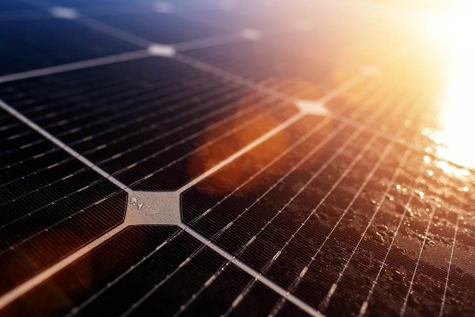 Primo piano di un pannello solare con la luce del sole che si riflette sulla sua superficie, collegato a un microinverter.