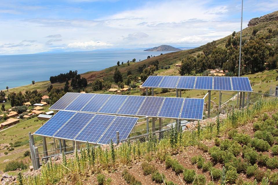 Pannelli solari, compreso un Easy Solar Kit, installati su una collina con vista su un grande lago sullo sfondo.